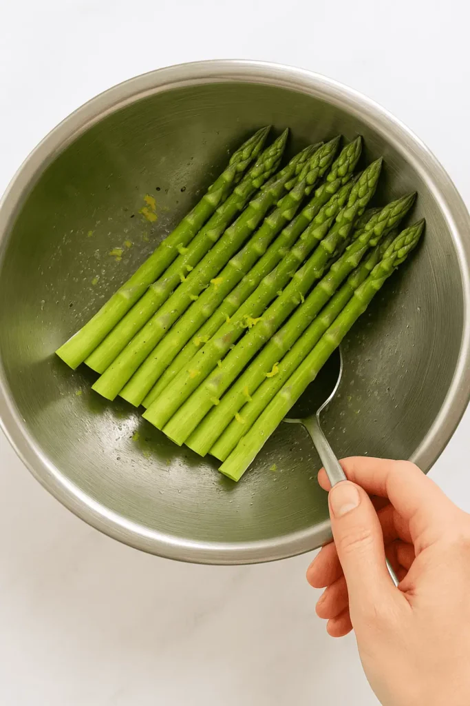 Toss asparagus with olive oil, lemon zest, salt, and pepper in a mixing bowl.